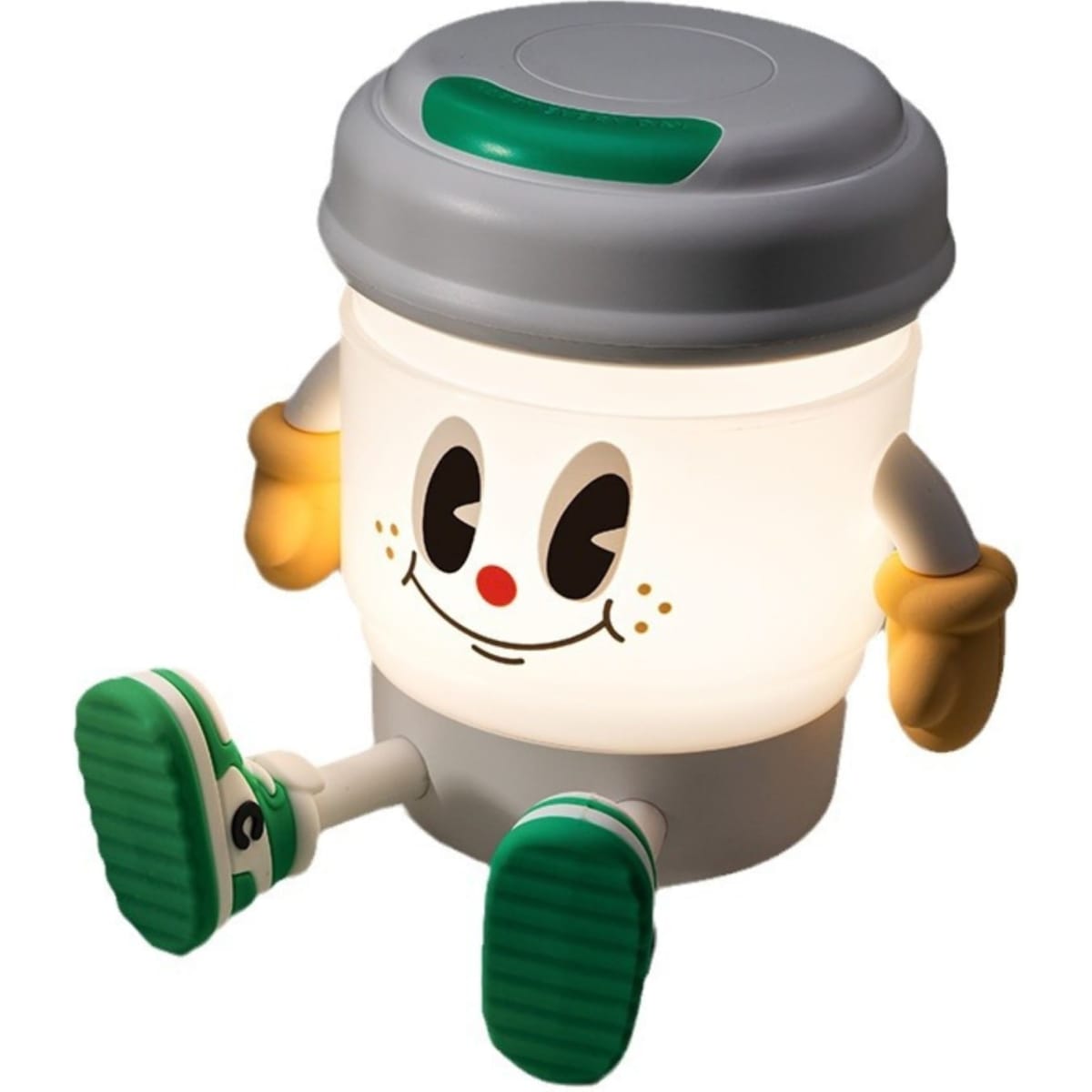 A light-up, coffee cup-shaped lamp features a friendly face with green accents and a base resembling a speaker.
