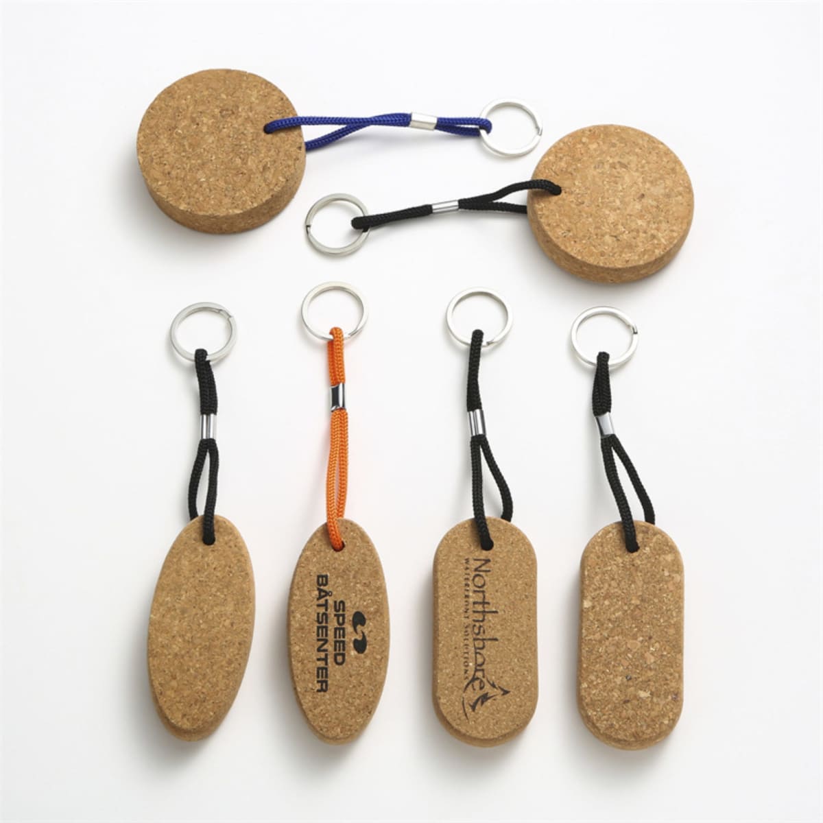 Cork floating key tags in various shapes with black, orange, and blue cords. Some feature branding.