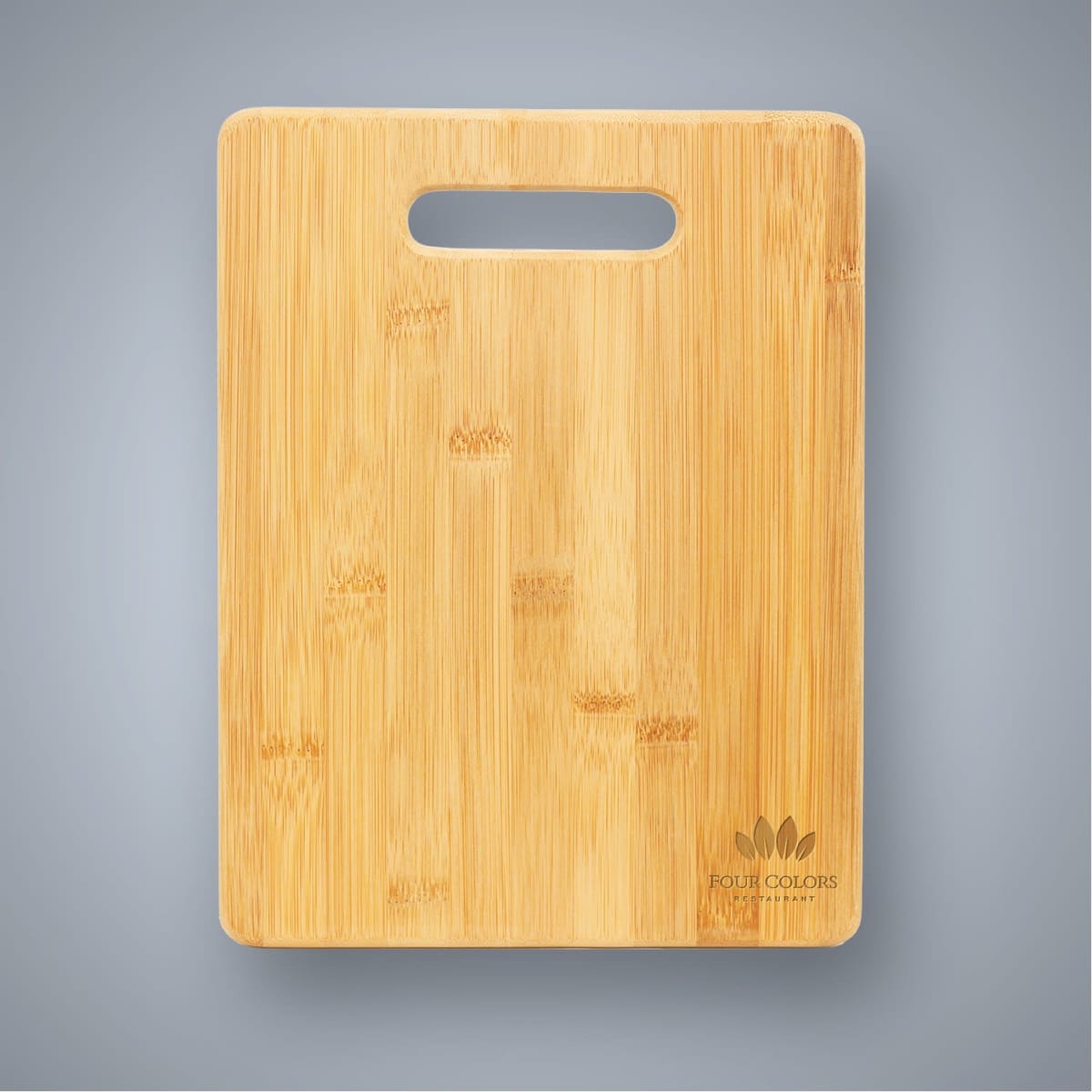 A large bamboo cutting board with a handle cutout, featuring a natural wood finish and a logo on the bottom corner.