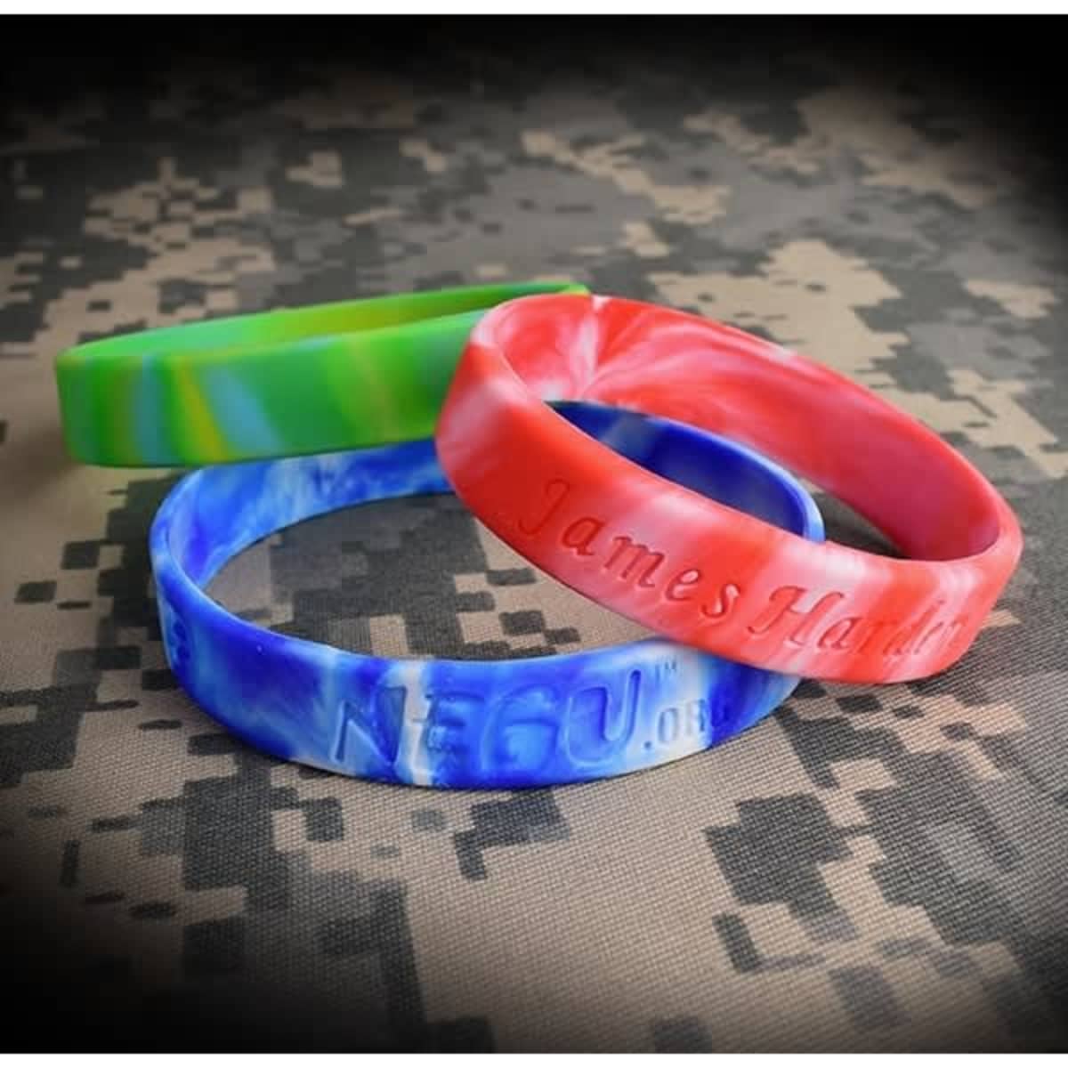 Three silicone wristbands in blue, red, and green swirl patterns, featuring embossed text and a logo.