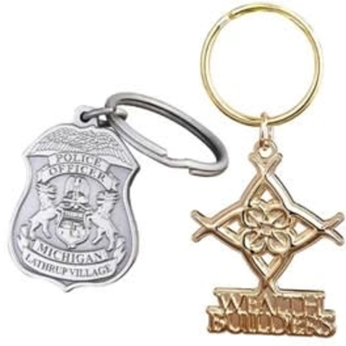 A silver police badge key chain and a gold "Wealth Builders" key chain, both on key rings.