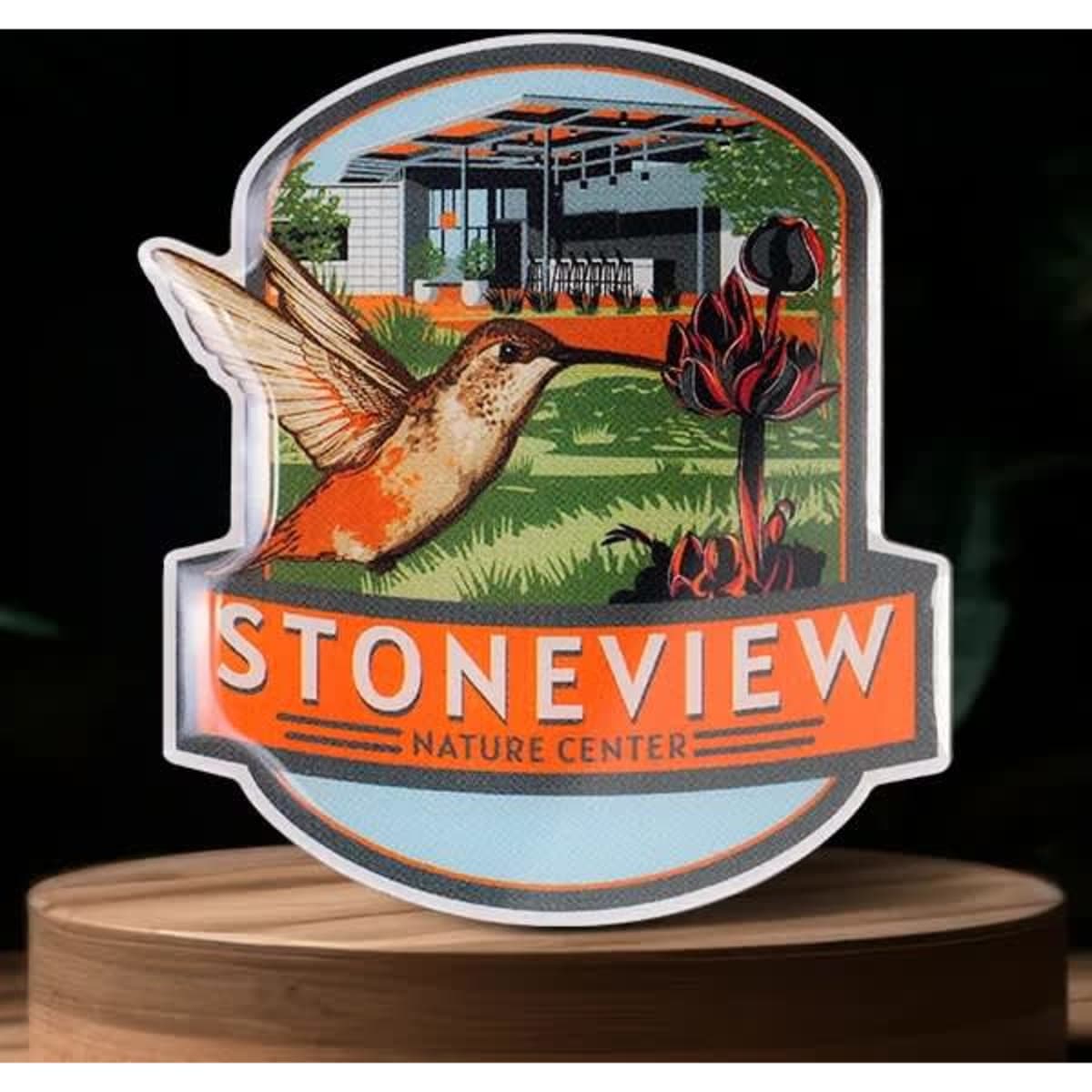 A promotional pin featuring a hummingbird, vibrant colours, and the logo for Stoneview Nature Center.