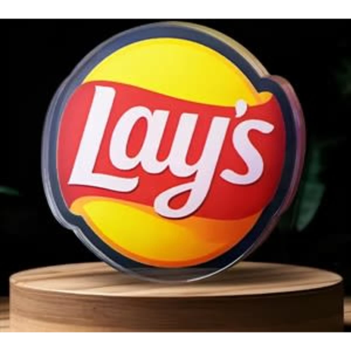 A round acrylic pin in yellow and red featuring the Lay's logo on a wooden display stand.