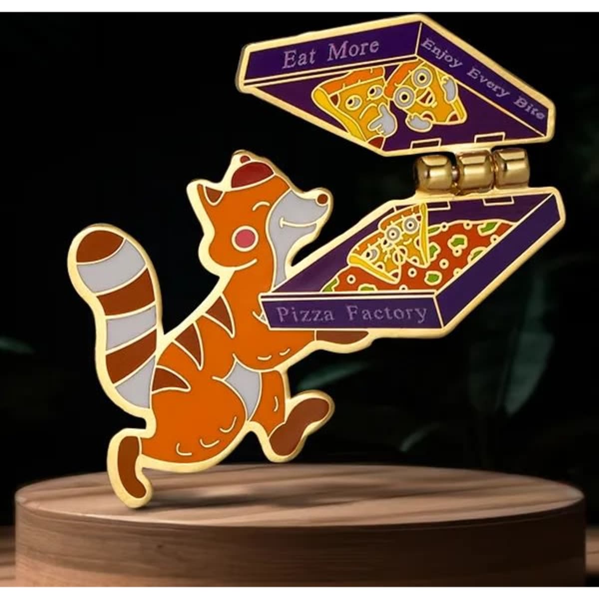 A colourful lapel pin featuring a cartoon fox holding a pizza box, with orange and purple accents.