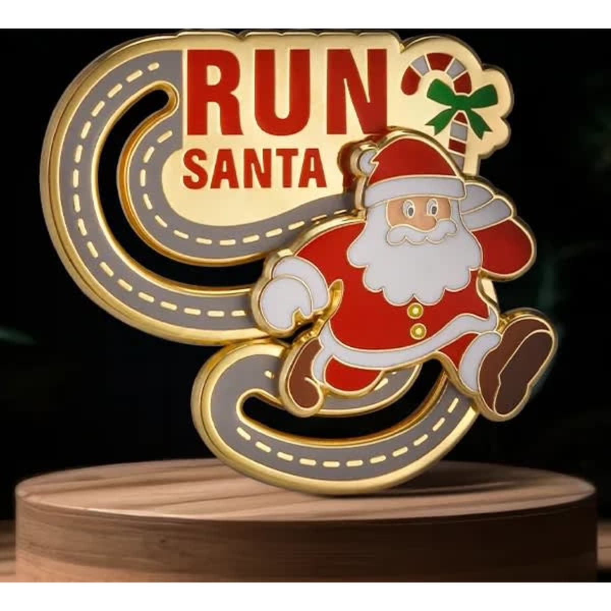 A gold and red lapel pin featuring a running Santa with a decorative candy cane and a winding path design.