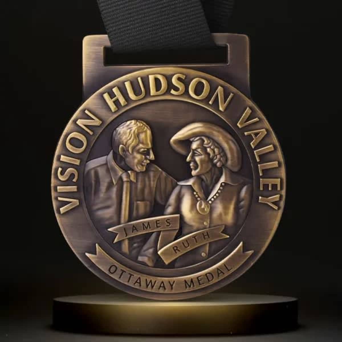 A bronze 3D medal featuring intricate designs of two people and a ribbon for wearing.
