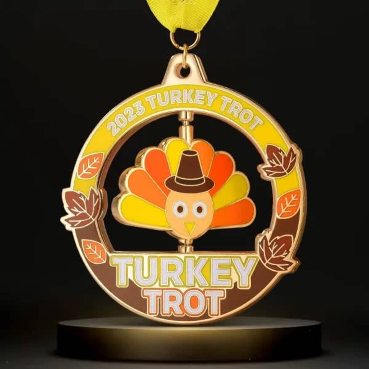 A gold spinner medal featuring a turkey design, with vibrant orange and yellow colours, and a yellow ribbon.