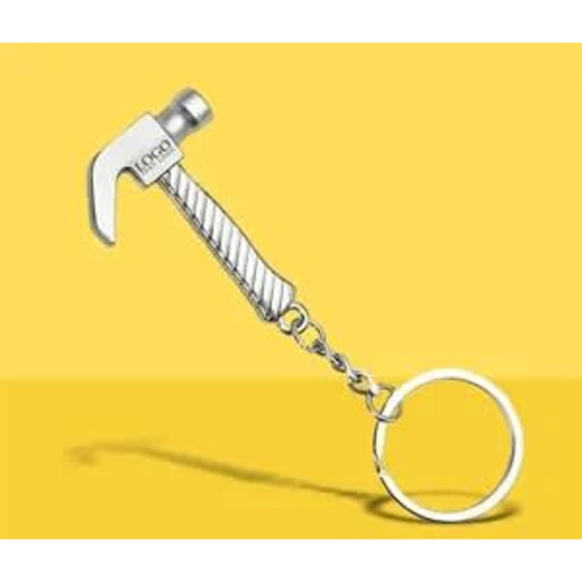 A silver hammer keychain with a textured handle and a circular metal ring, set against a yellow background.