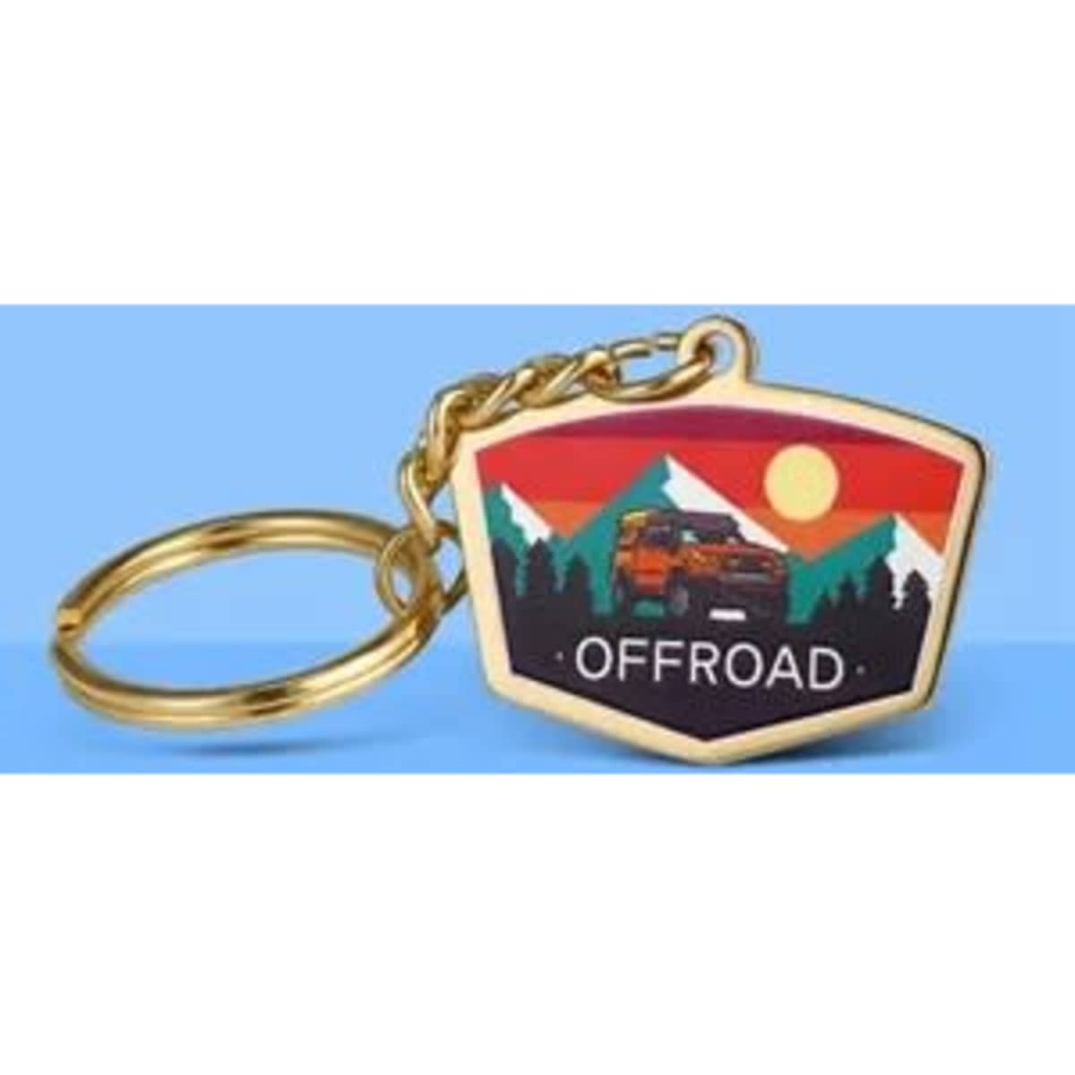 A metal print keychain in a gold tone featuring an off-road vehicle against a mountain sunset design.