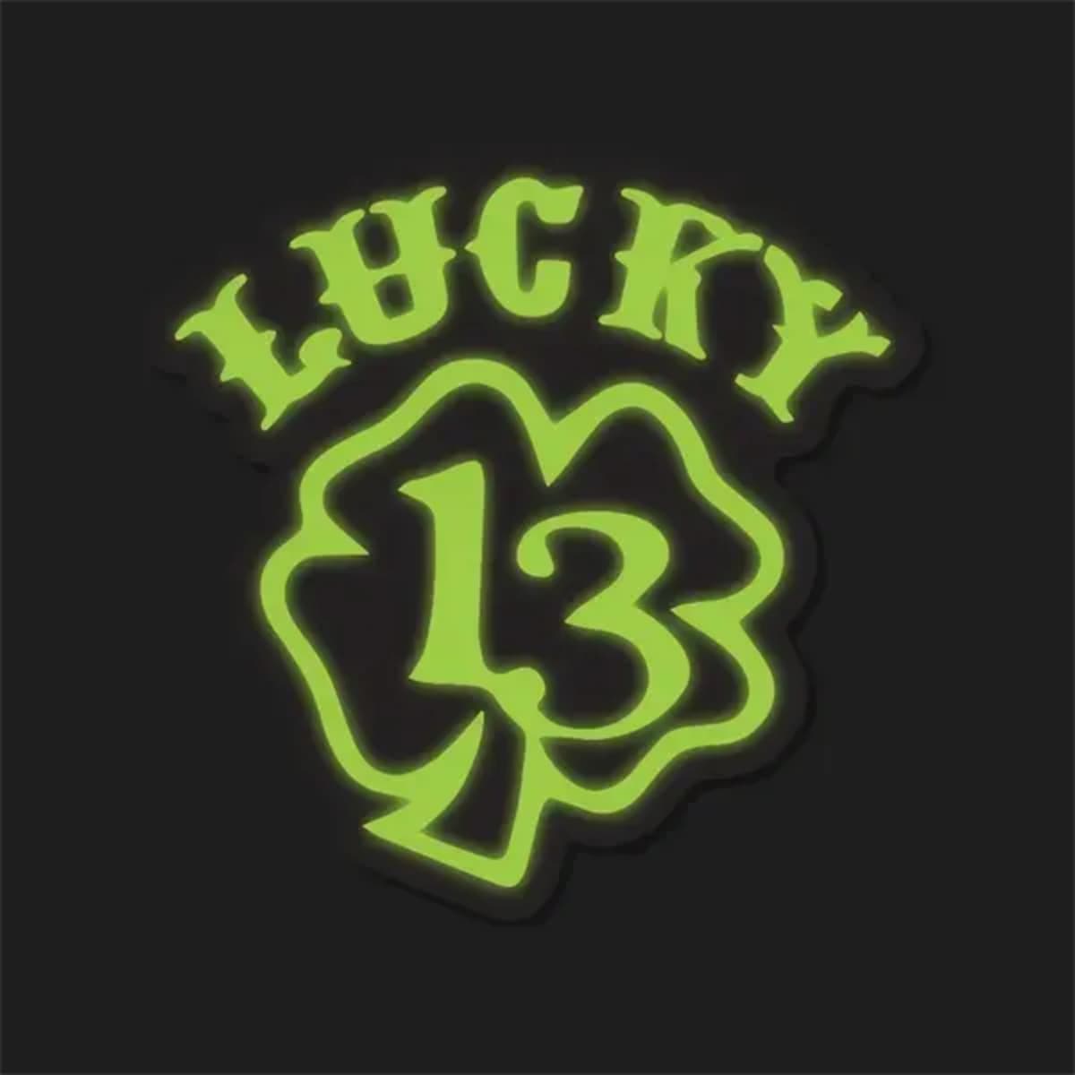 A green glow-in-the-dark sticker featuring the text "LUCKY" above a clover design with the number "13" inside.