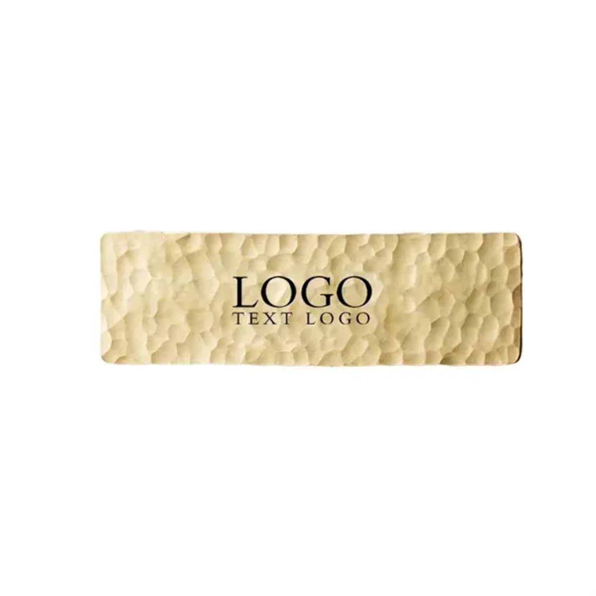 A rectangular brass name badge with a textured surface and a logo. The colour is a polished brass tone.