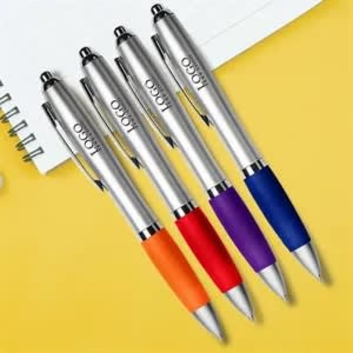 Four satin stylus pens in silver, orange, red, and purple, displayed with a notebook on a yellow background.