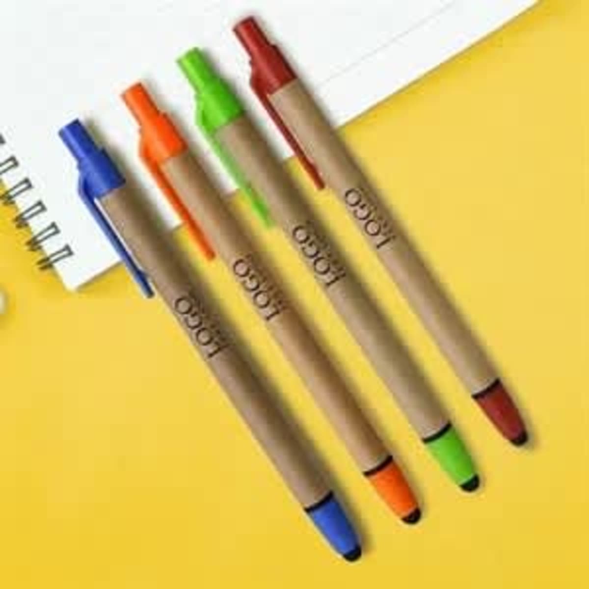 Four recycled ballpoint stylus pens in blue, orange, green, and red with a kraft paper body on a yellow background.