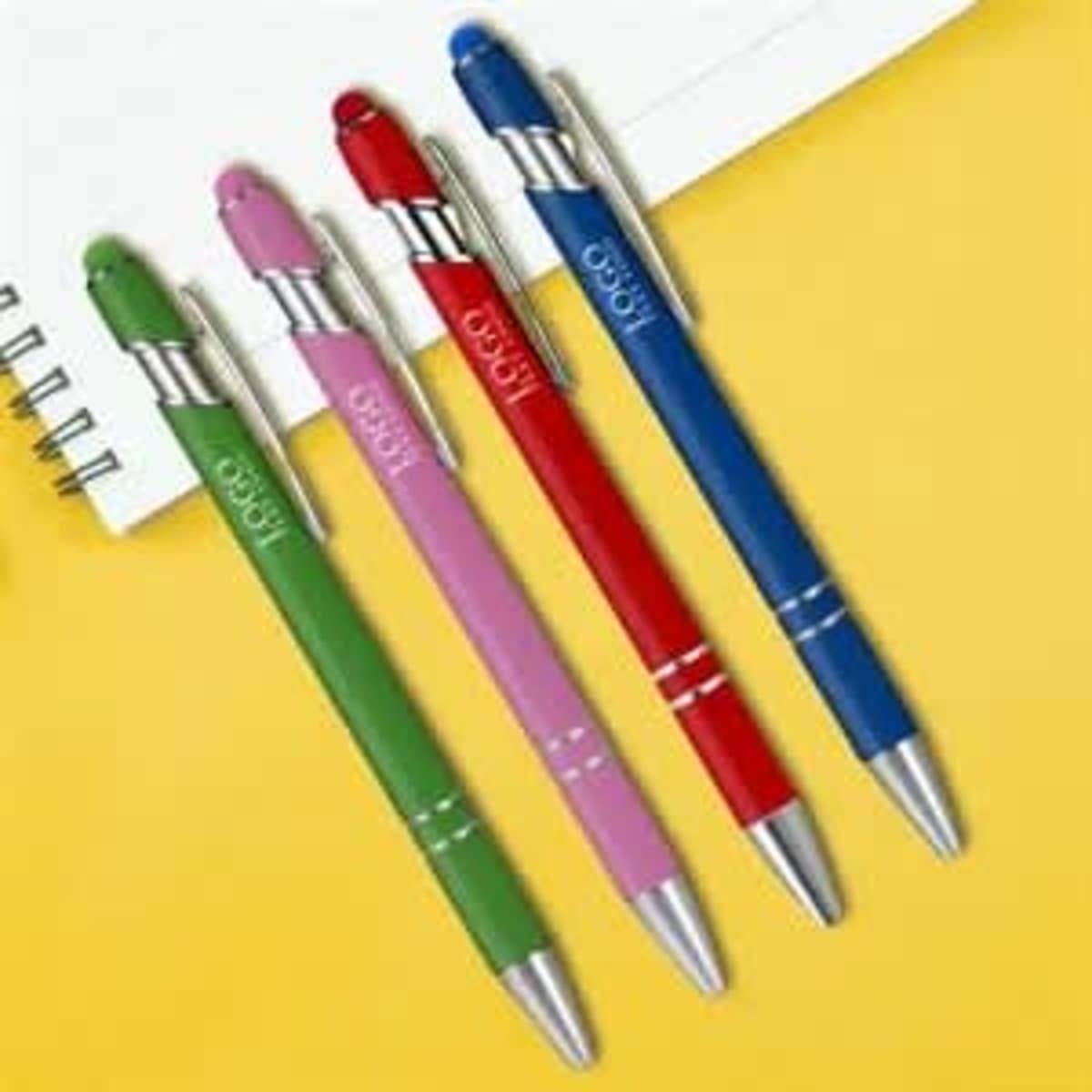 A selection of four metal ballpoint pens in green, pink, red, and blue, each with a stylus tip and a logo.