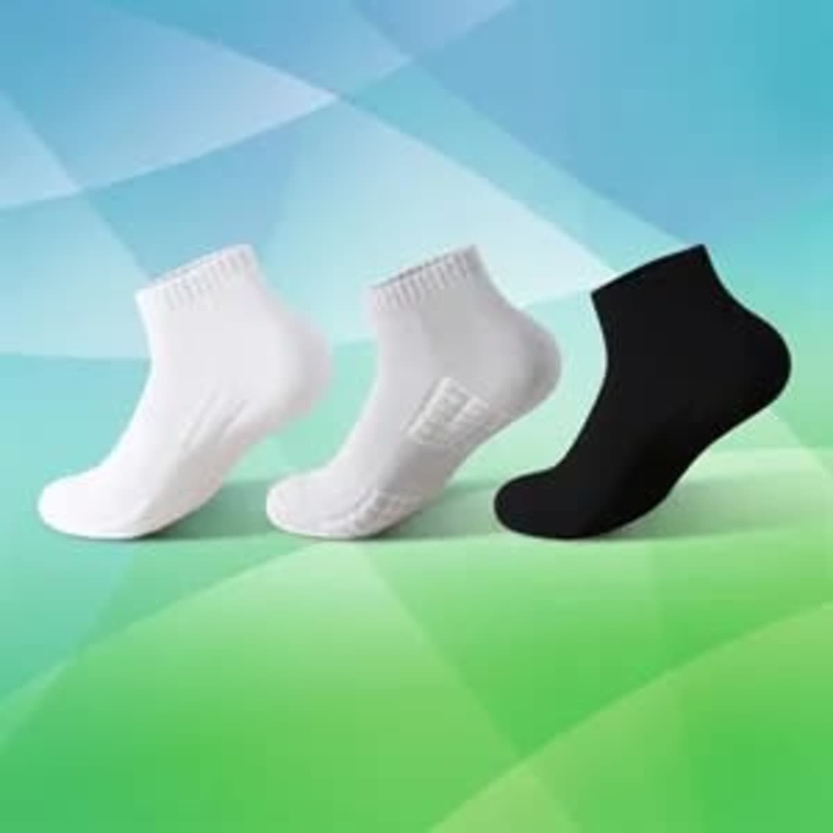 Three pairs of low cut cushioned sports socks in white and black against a colourful background.