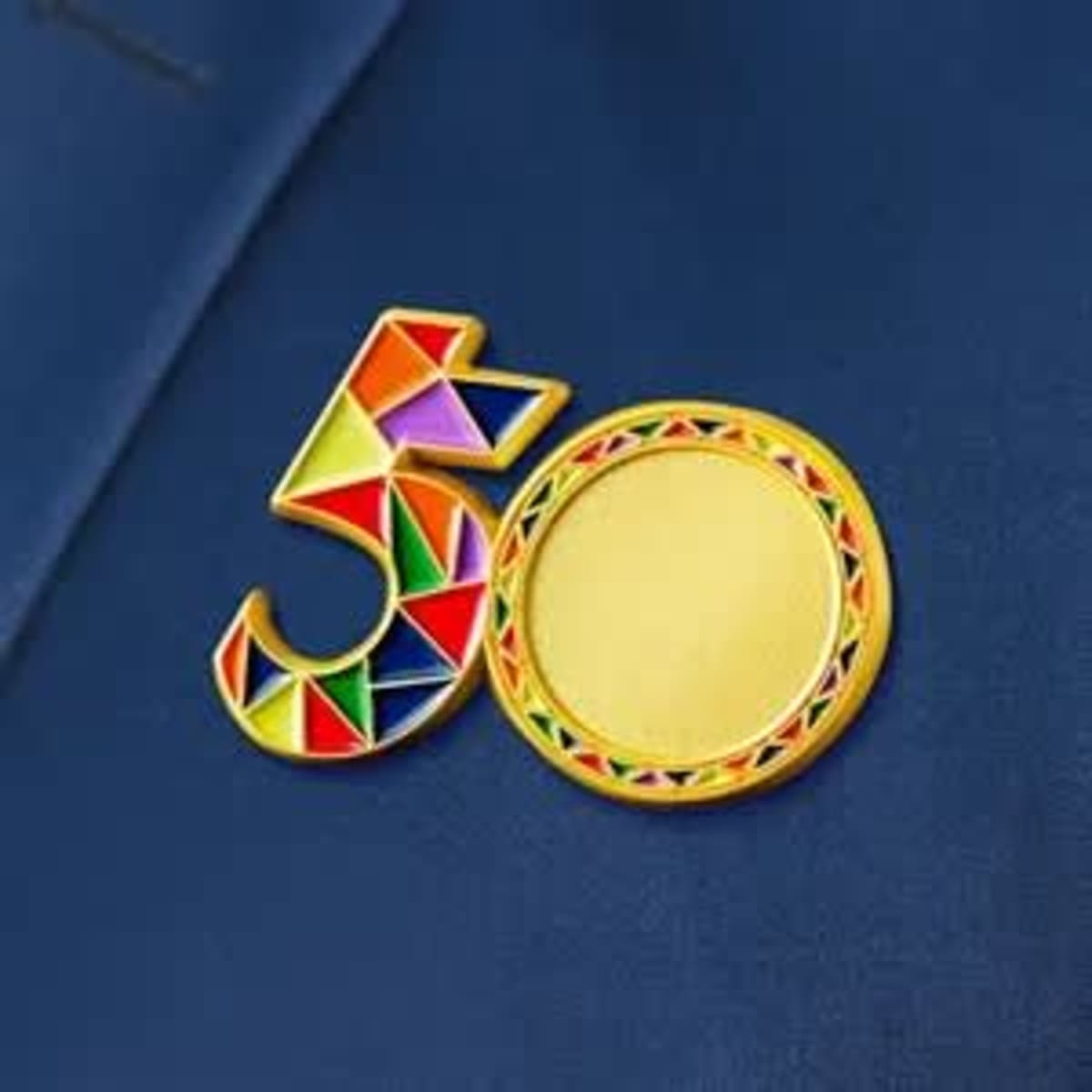 A vibrant metal name badge featuring a colourful geometric design and a circular gold area.
