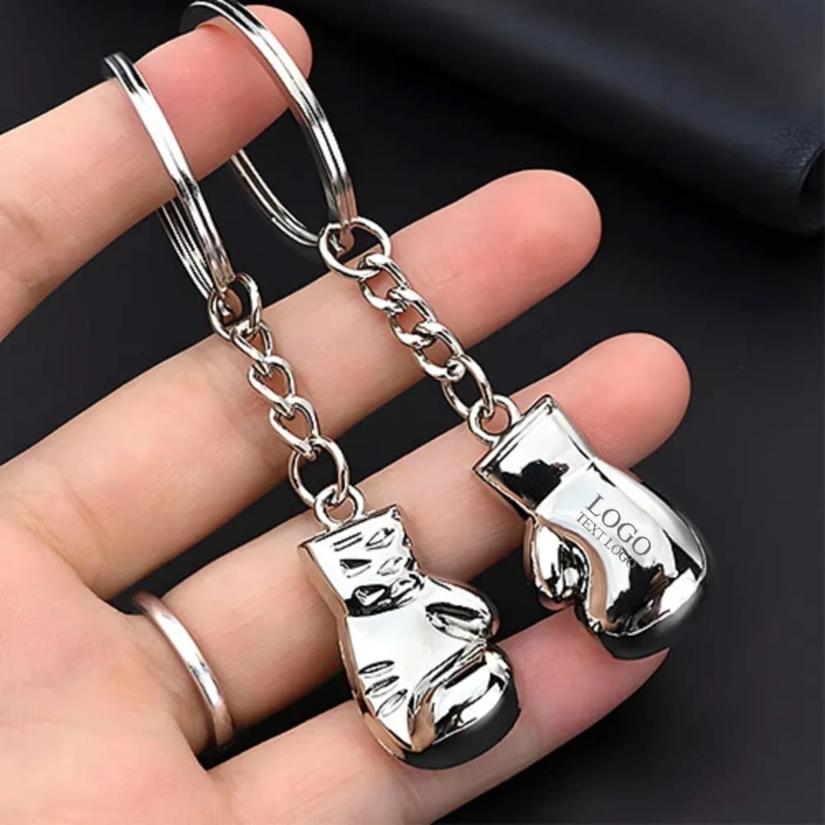 A shiny silver key chain featuring two small boxing glove-shaped charms, connected by a metal chain.