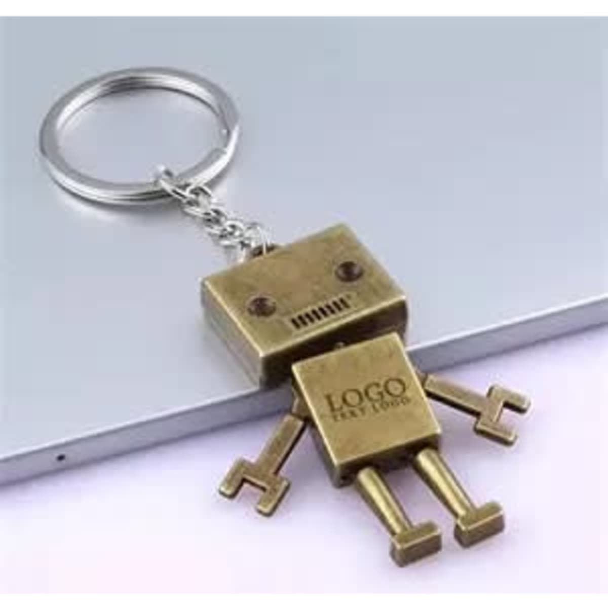 A robot-shaped key chain in gold with a metallic finish and movable arms and legs, attached to a keyring.
