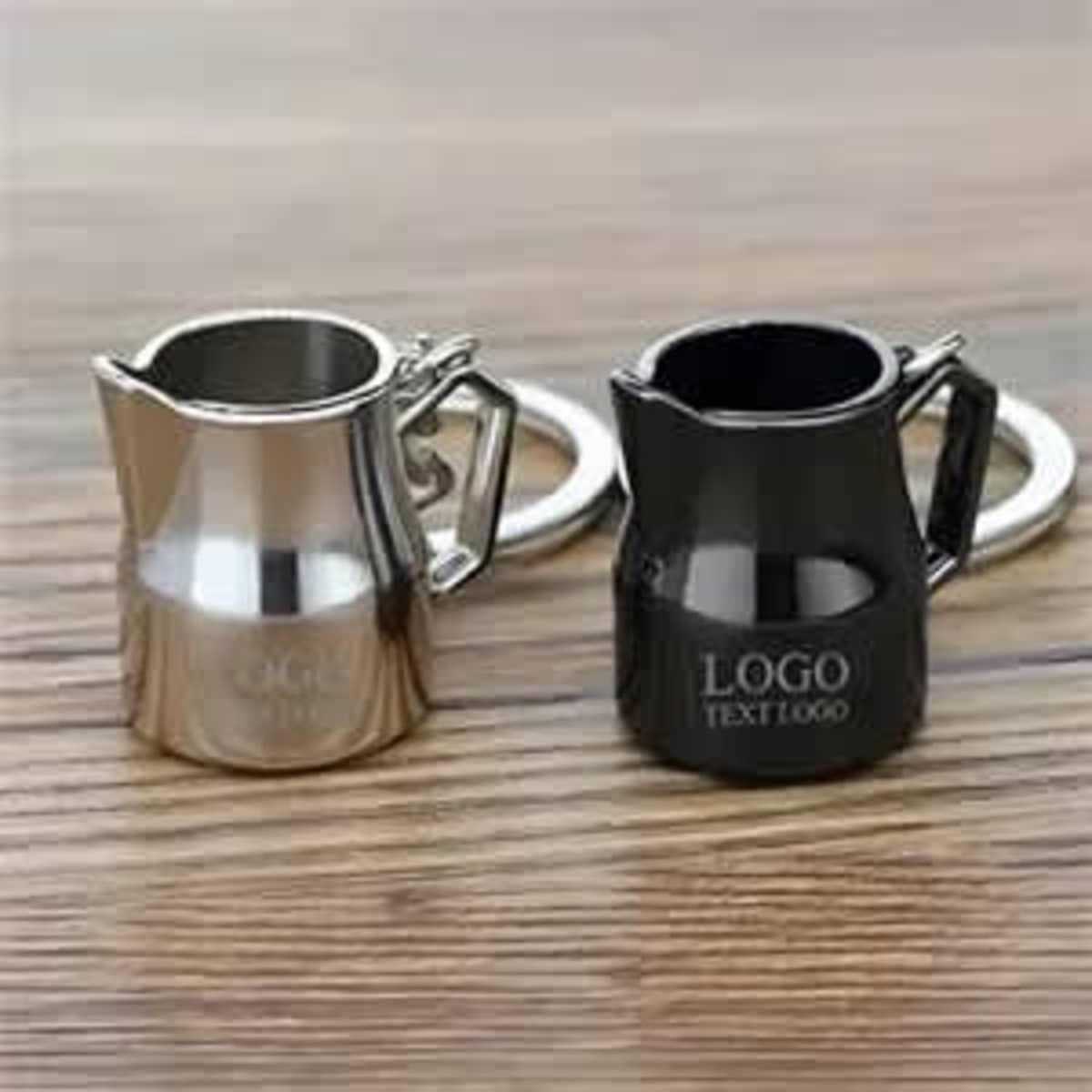 A silver and black alloy key chain shaped like a coffee cup, with a small handle and logo details.