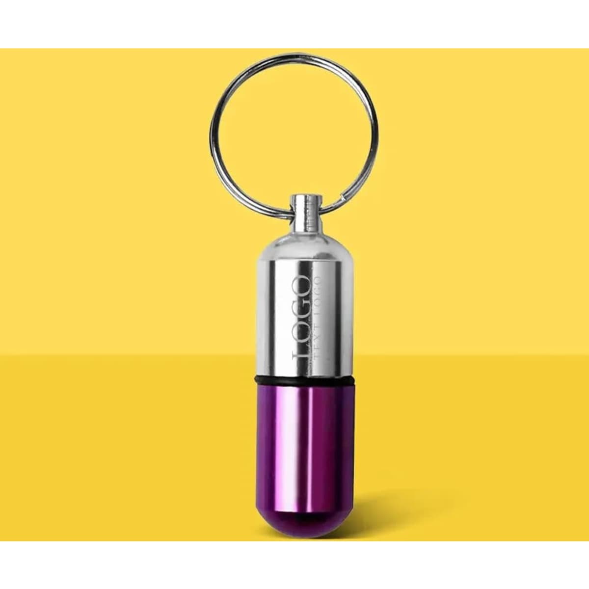 A purple and silver aluminium pill case keychain with a metal ring and a logo.