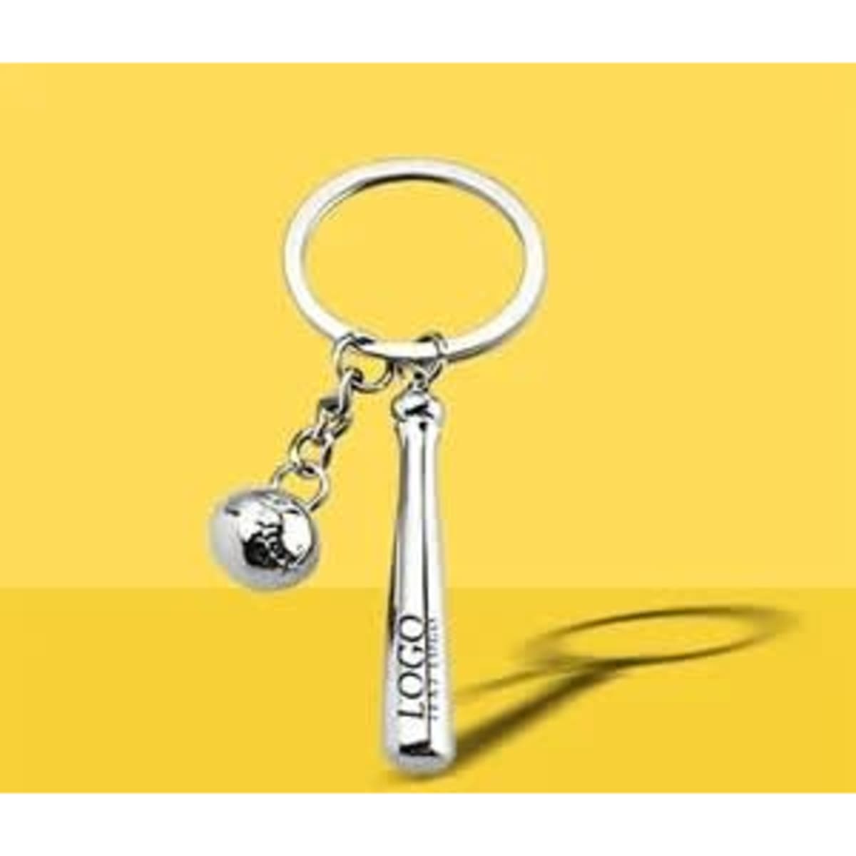 A silver keychain featuring a mini bat and baseball, attached to a round ring, set against a yellow background.