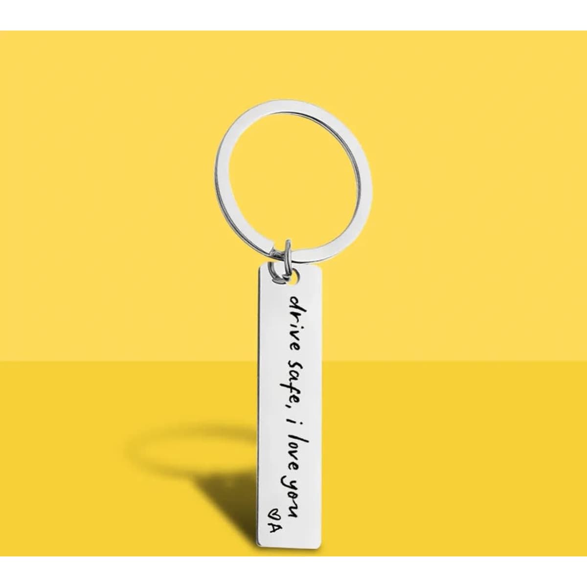 A custom stainless steel keychain featuring an engraved message on a rectangular pendant and a circular keyring.