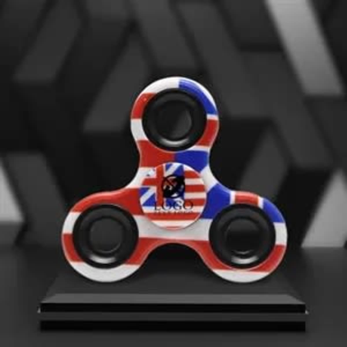 A hand finger spinner featuring a red, white, and blue design, displayed on a black pedestal.