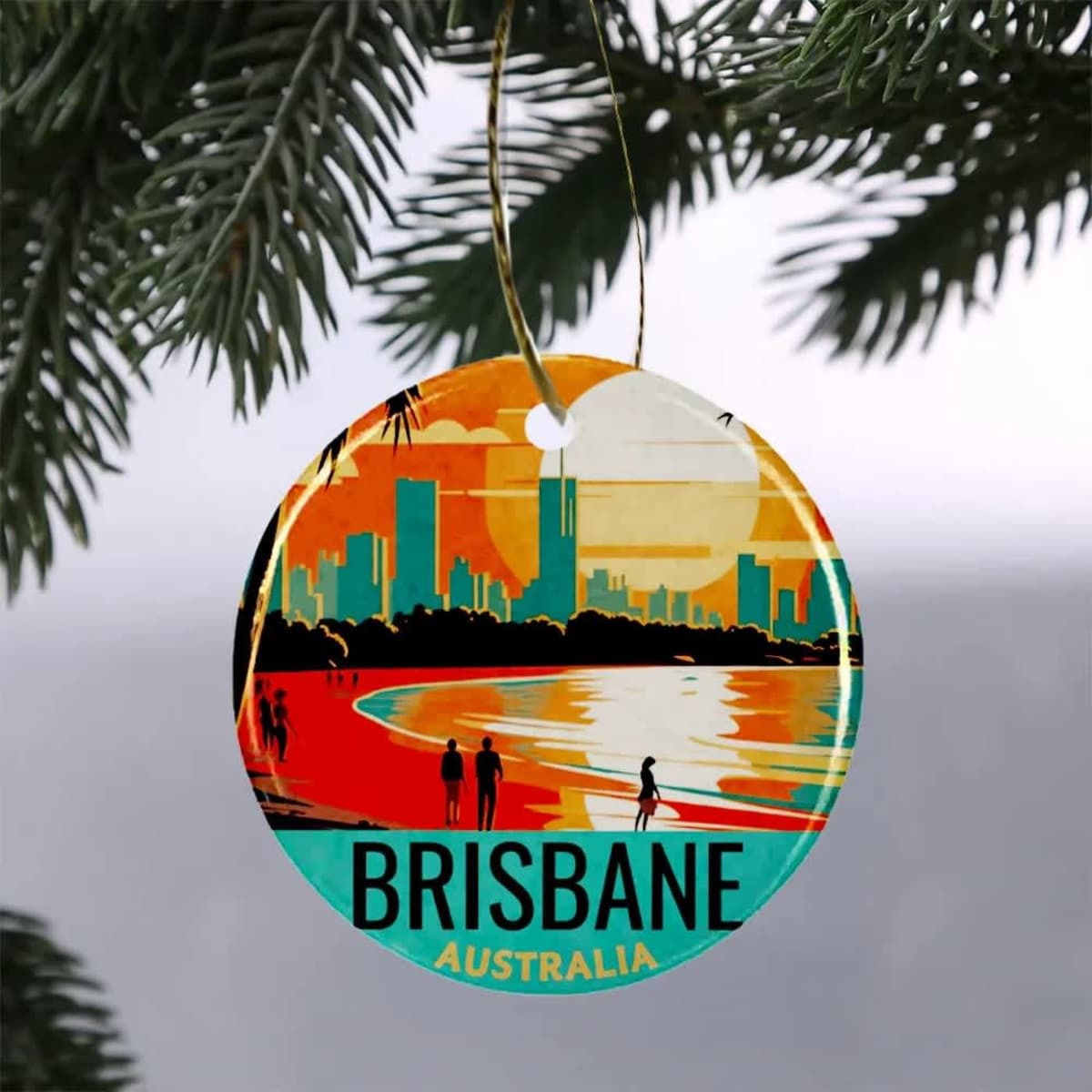 A circular ceramic ornament featuring a vibrant sunset over Brisbane's skyline, with people along the beach.