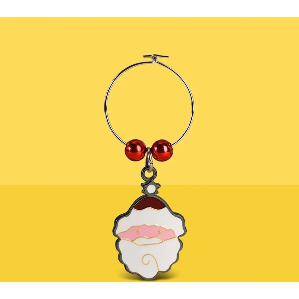 A silver wine charm featuring a Santa face design with red beads, set against a yellow background.