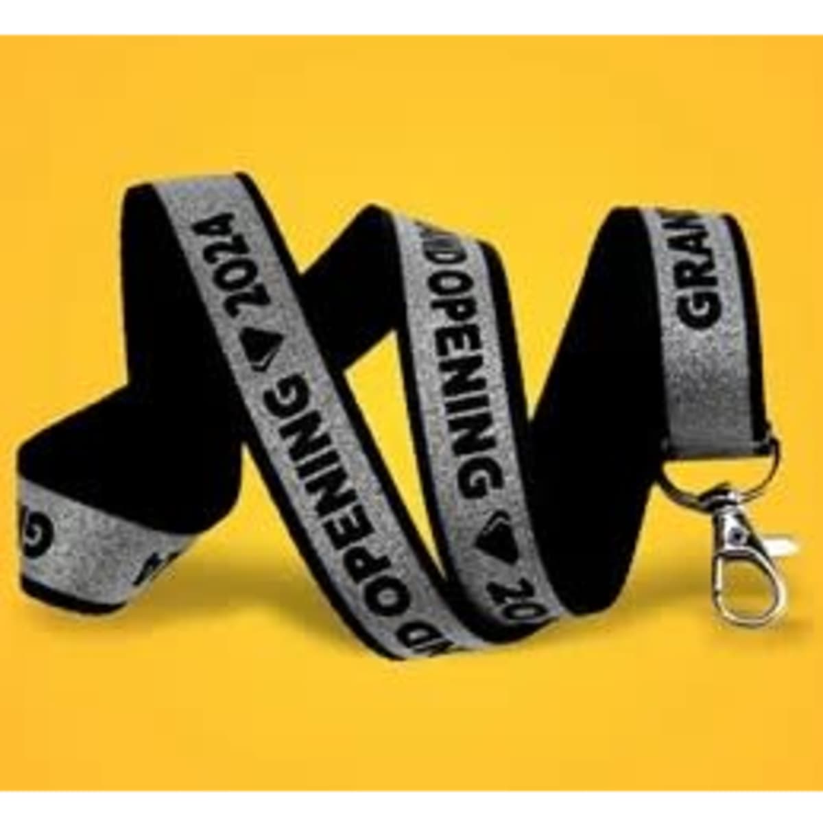 A glittery black and silver lanyard with a clip, featuring text for a grand opening event.