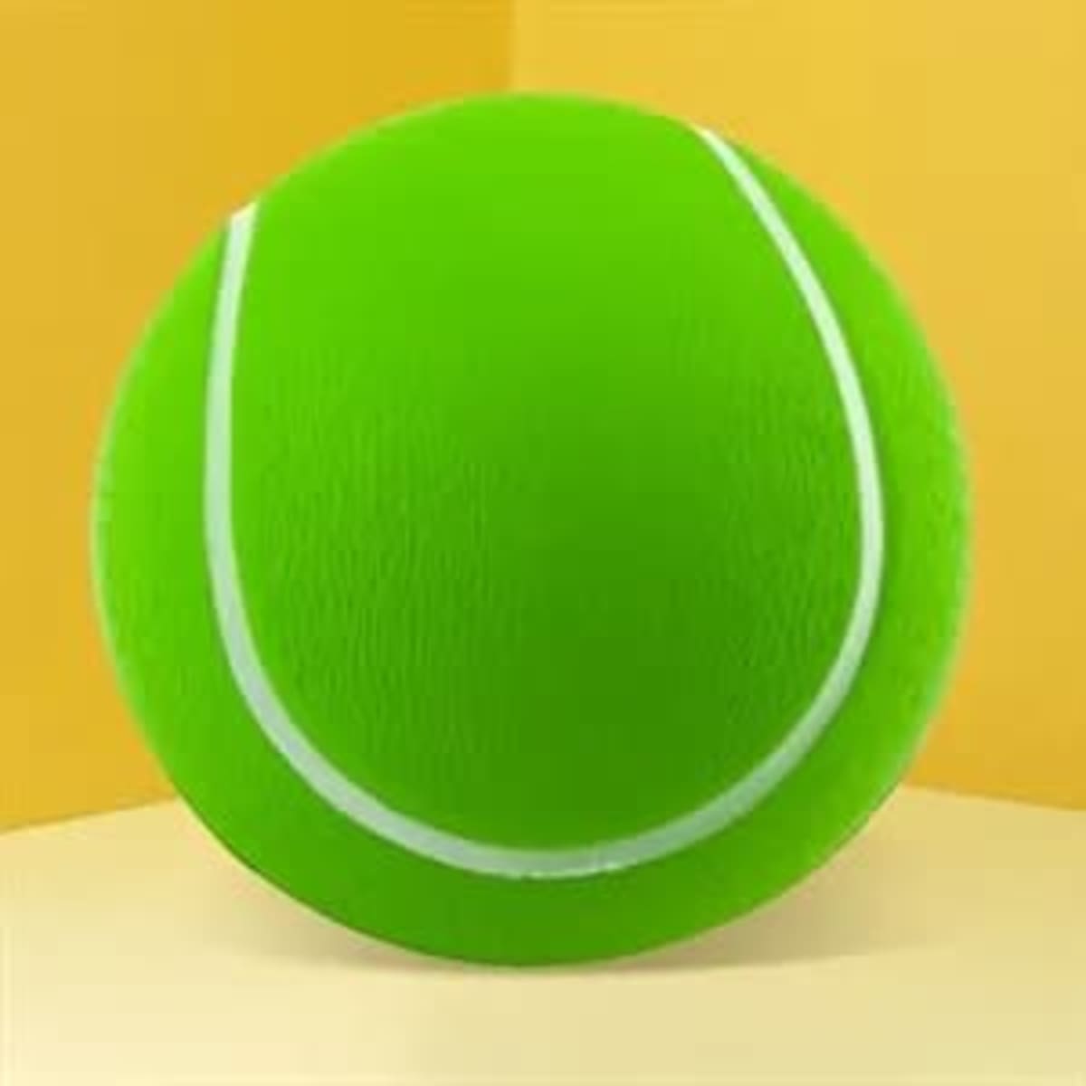 A bright green tennis stress ball with white markings, displayed against a yellow background.
