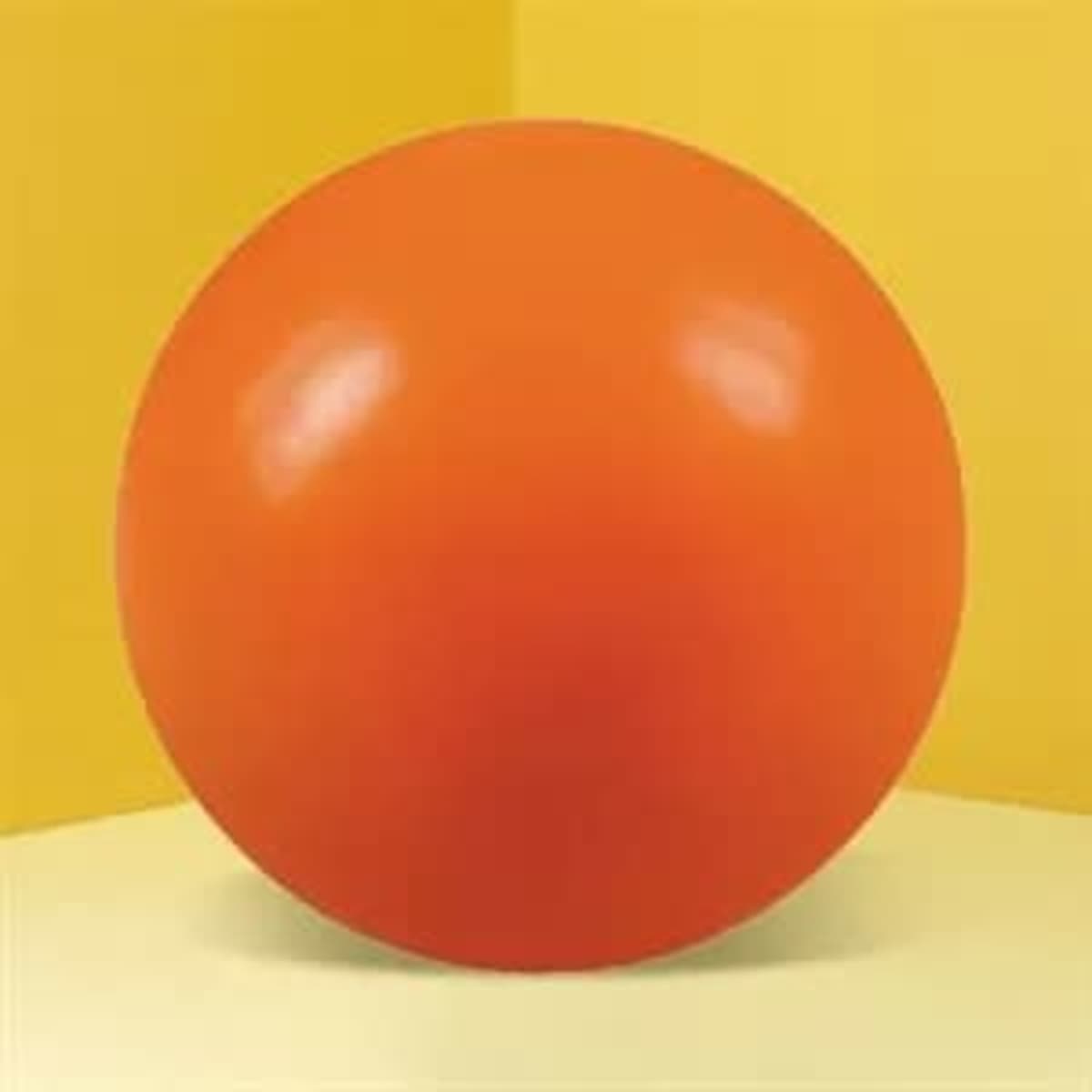 An orange round stress ball with a glossy finish, set against a yellow background.