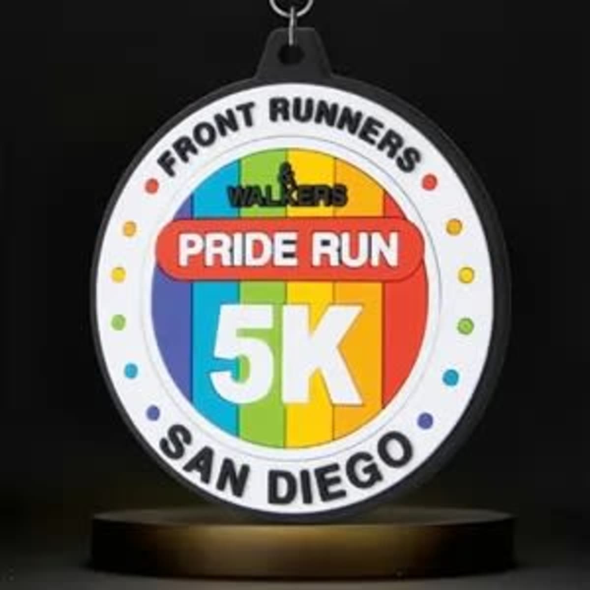 A round, multicoloured PVC medal featuring rainbow stripes and a logo, hanging from a black ribbon.
