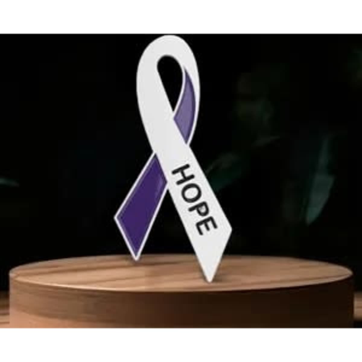 A purple and white awareness ribbon lapel pin featuring the word "HOPE". It is set on a wooden surface.