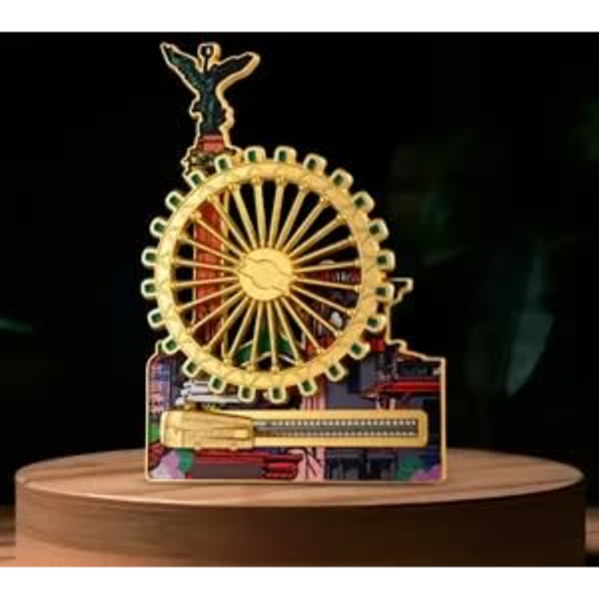 A decorative model featuring a golden ferris wheel atop a vibrant city skyline, with intricate detailing and a logo.
