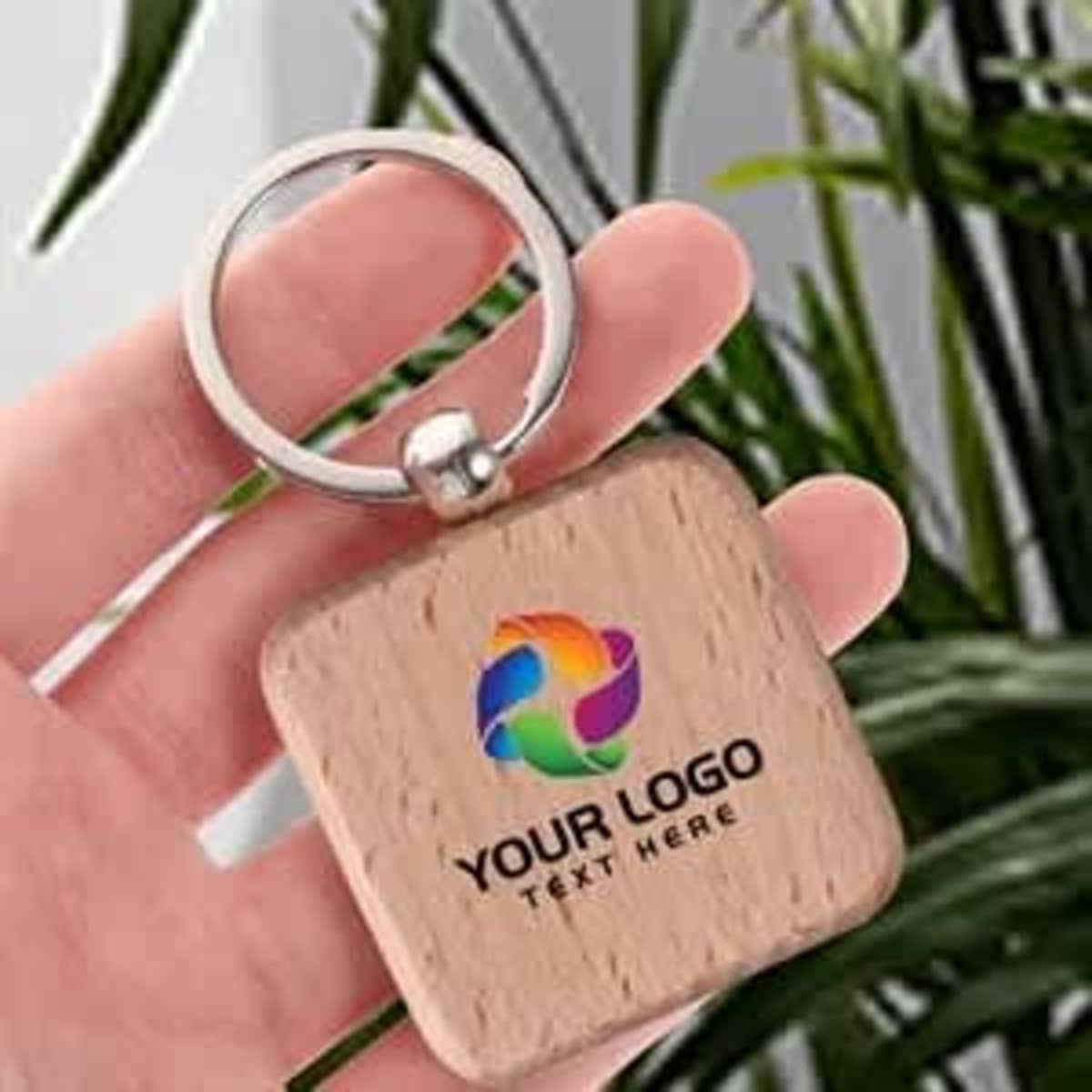 A wooden key holder with a square design, featuring a metal ring and a colourful logo.
