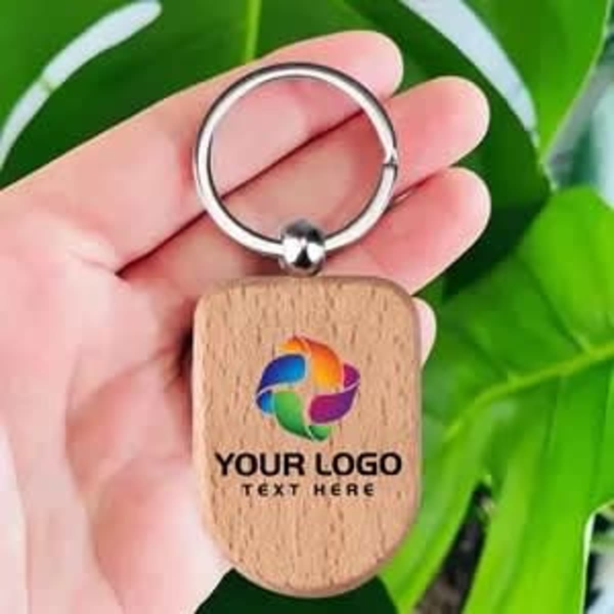 A wooden key holder with a silver keyring, featuring a colourful logo and text on a light wood background.