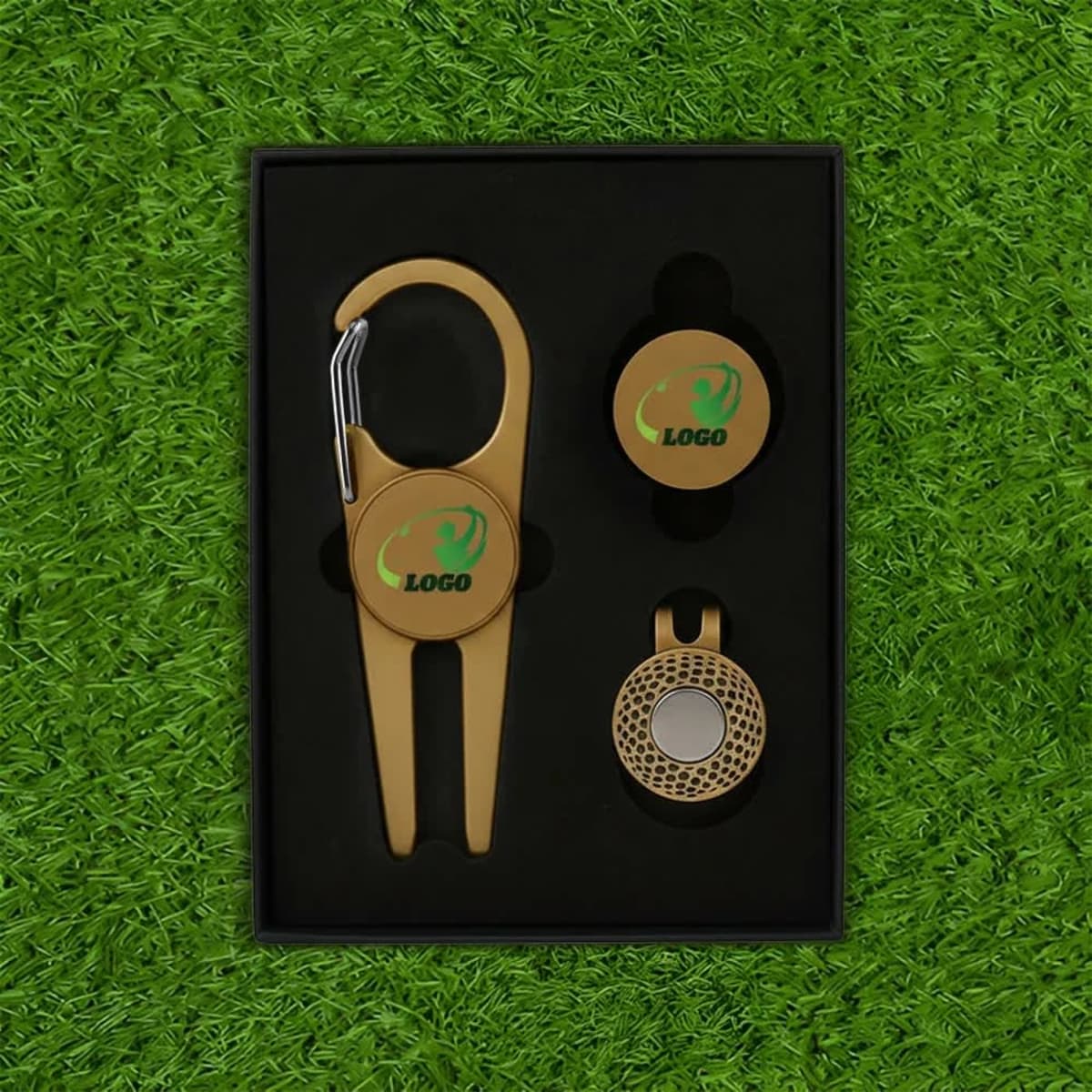 A gold magnetic golf tool set with a carabiner, including ball markers, arranged in a black box.