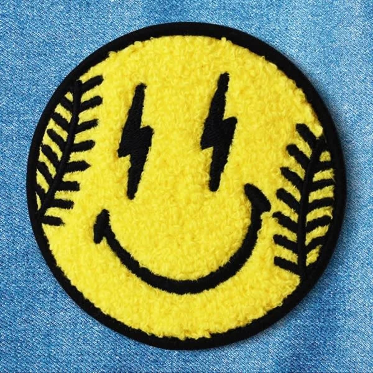 A round, yellow chenille patch featuring a smiling face with black lightning bolts and leaf designs.