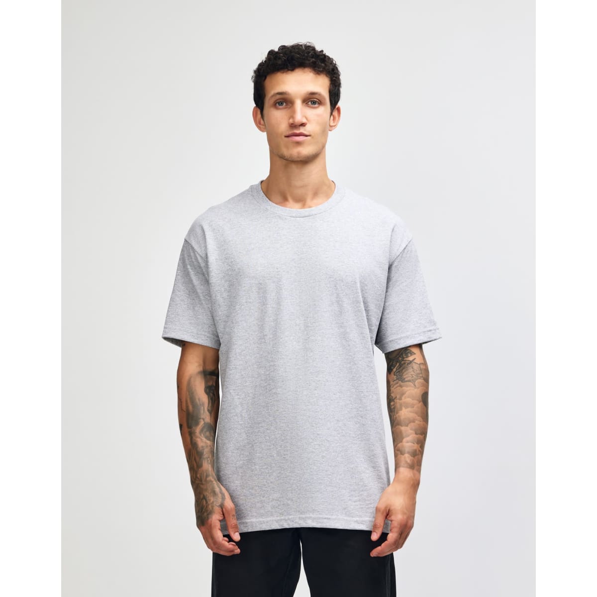 A heavyweight cotton unisex T-shirt in grey, featuring short sleeves and a relaxed fit. It has a logo on it.