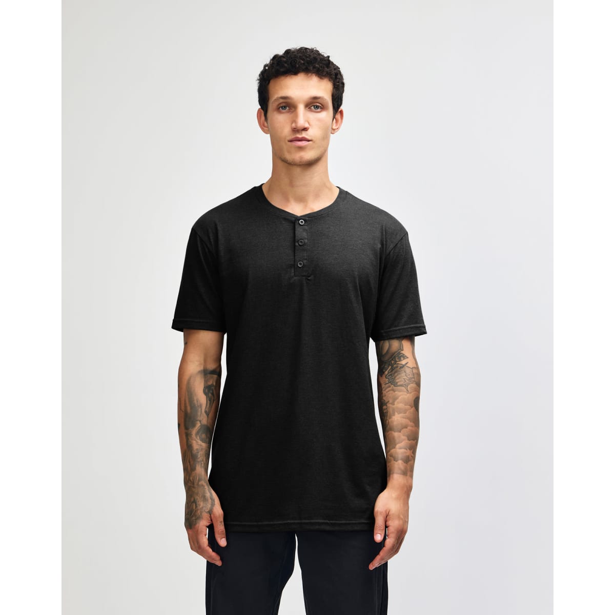 A black unisex Henley T-shirt featuring a button placket and short sleeves, modelled by a person.