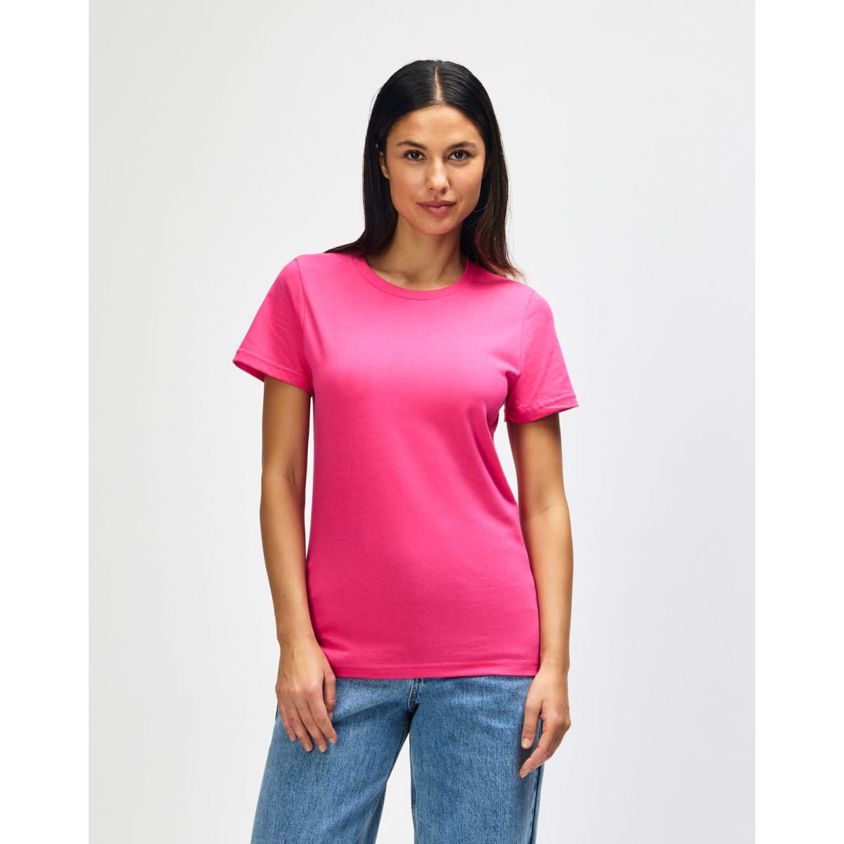 A pink Gildan Softstyle ladies midweight T-shirt displayed on a model, featuring a simple design and a logo.