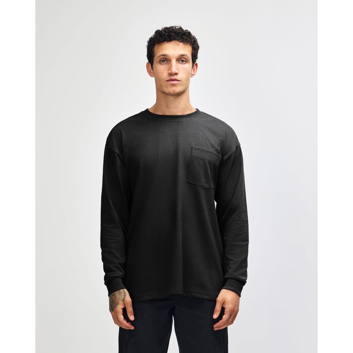 A black long-sleeve t-shirt with a pocket, featuring a subtle logo on the front.