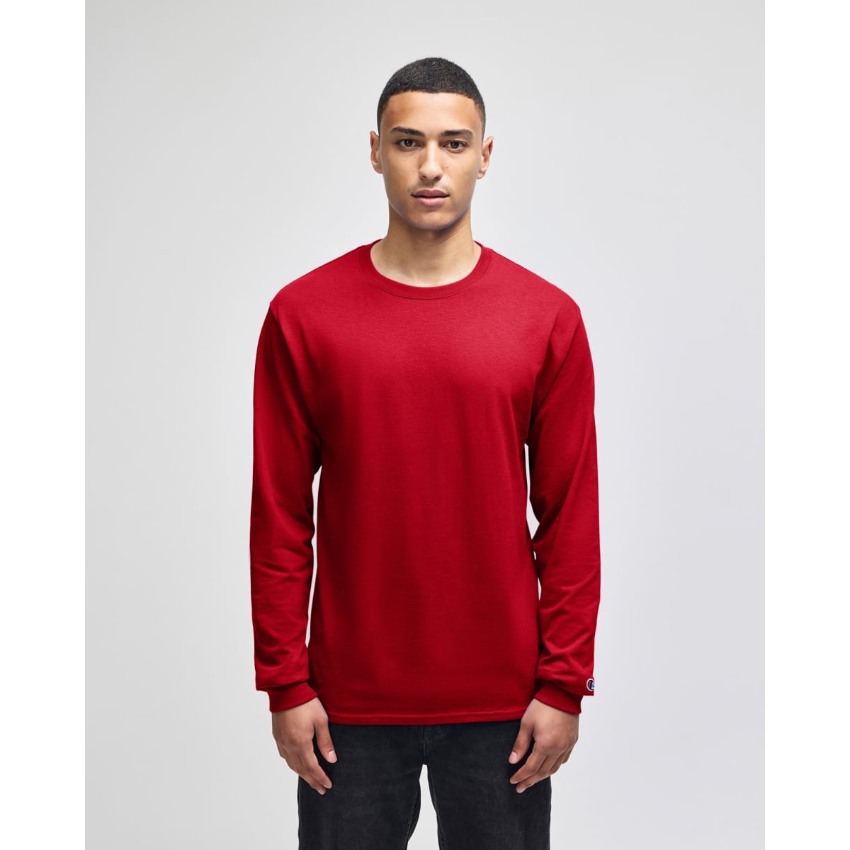 A red long-sleeve t-shirt featuring a logo on the sleeve, presented on a model against a plain background.