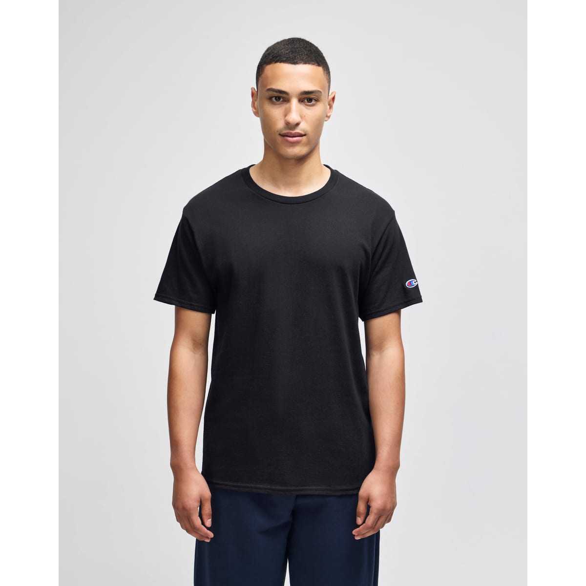 A black adult jersey short sleeve t-shirt with a logo on the sleeve, displayed on a model.