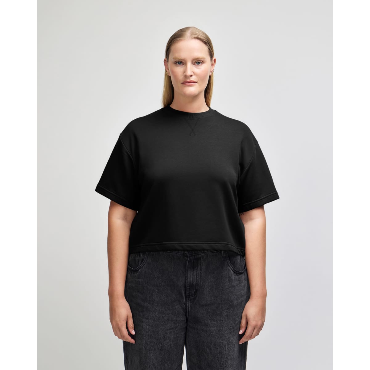 A black, mid-length boxy top for women made of French terry material, featuring a relaxed fit and short sleeves.