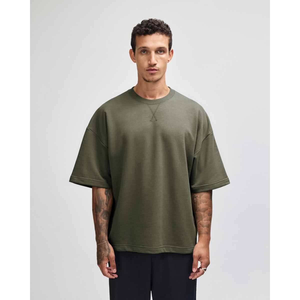 A unisex oversized boxy top in olive green with a crew neckline and finished seams. It features a logo.