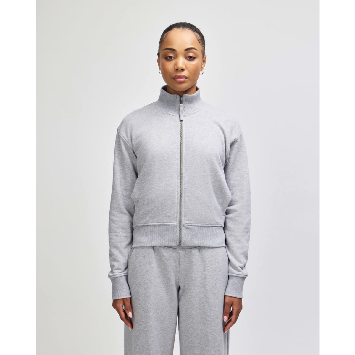A grey full-zip jacket with a stand collar, featuring a fitted design and long sleeves. Contains a logo.