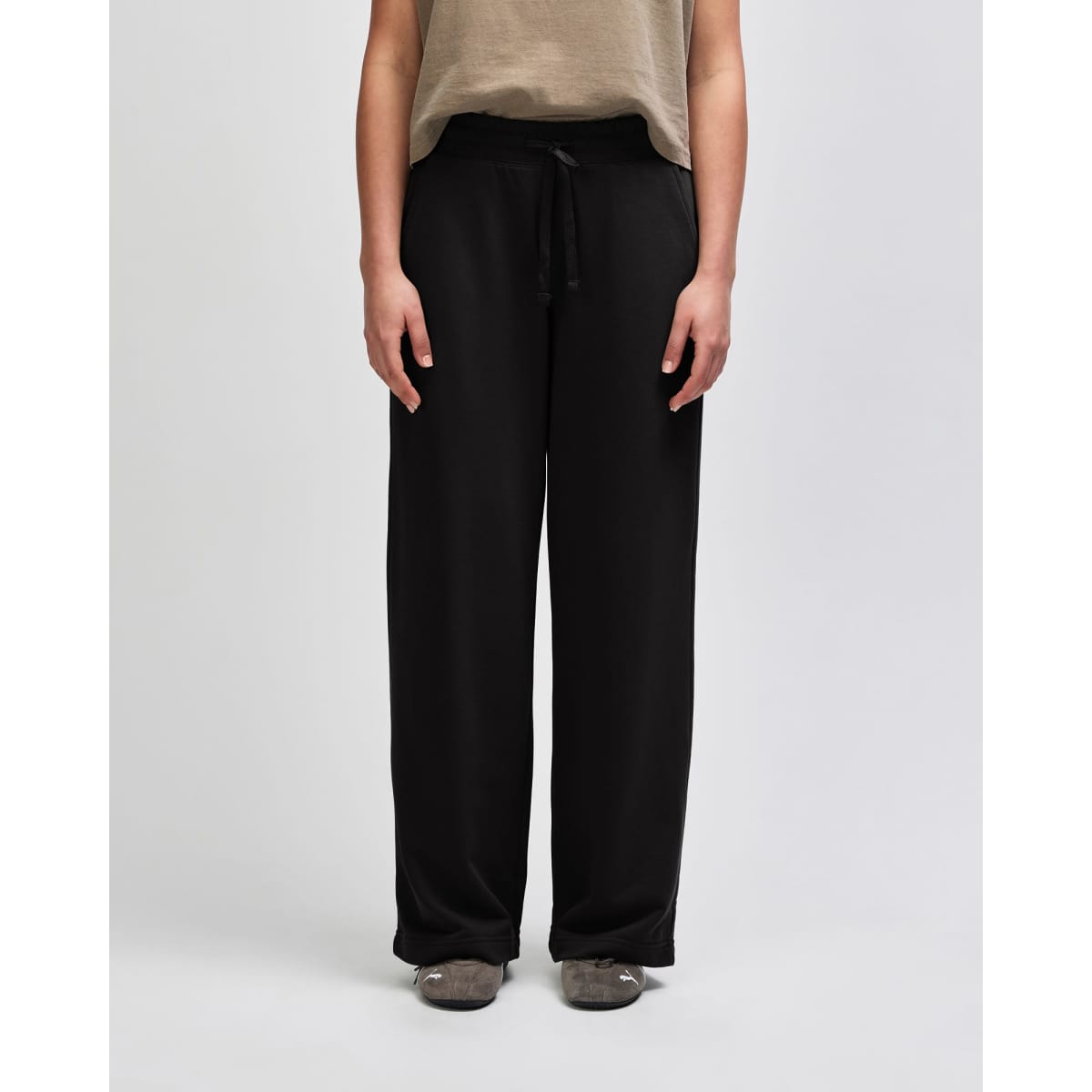 Wide leg pants in black with a drawstring waist, featuring a relaxed fit and pockets. The model is wearing a long-sleeved top.