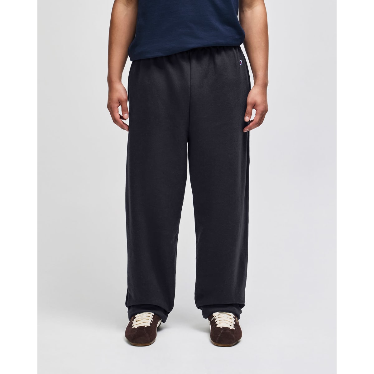 Open-bottom fleece pants in black, featuring pockets and an elastic waistband, worn by a person standing.